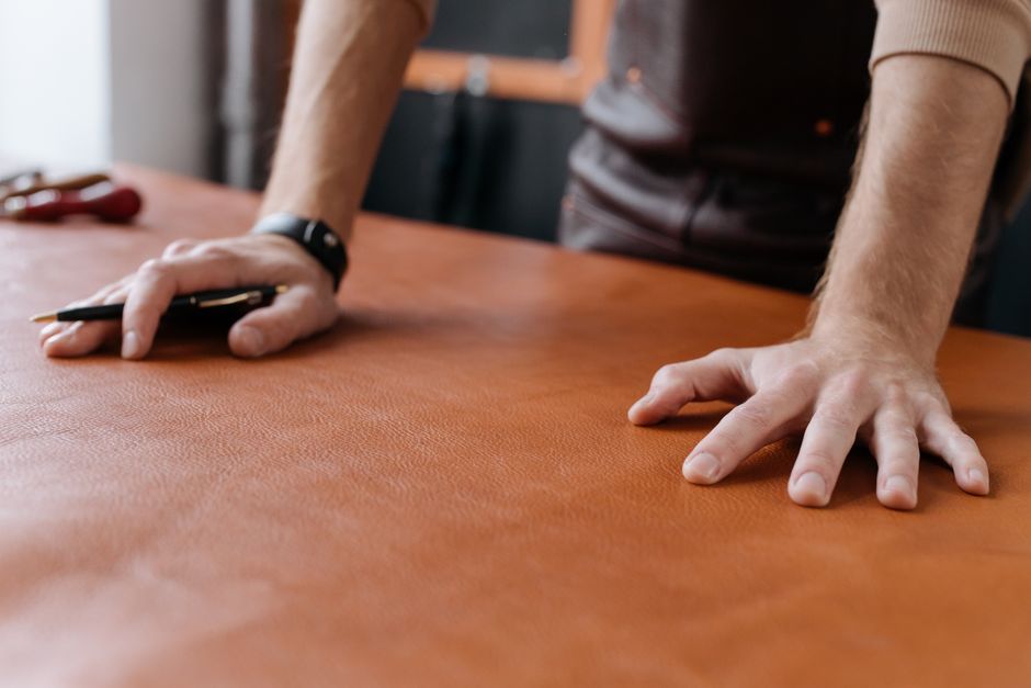 Detailed shot of a leatherworker’s hands working with brown leather, highlighting craftsmanship and precision.
